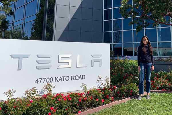 Rachel Joseph standing next to the Tesla sign.